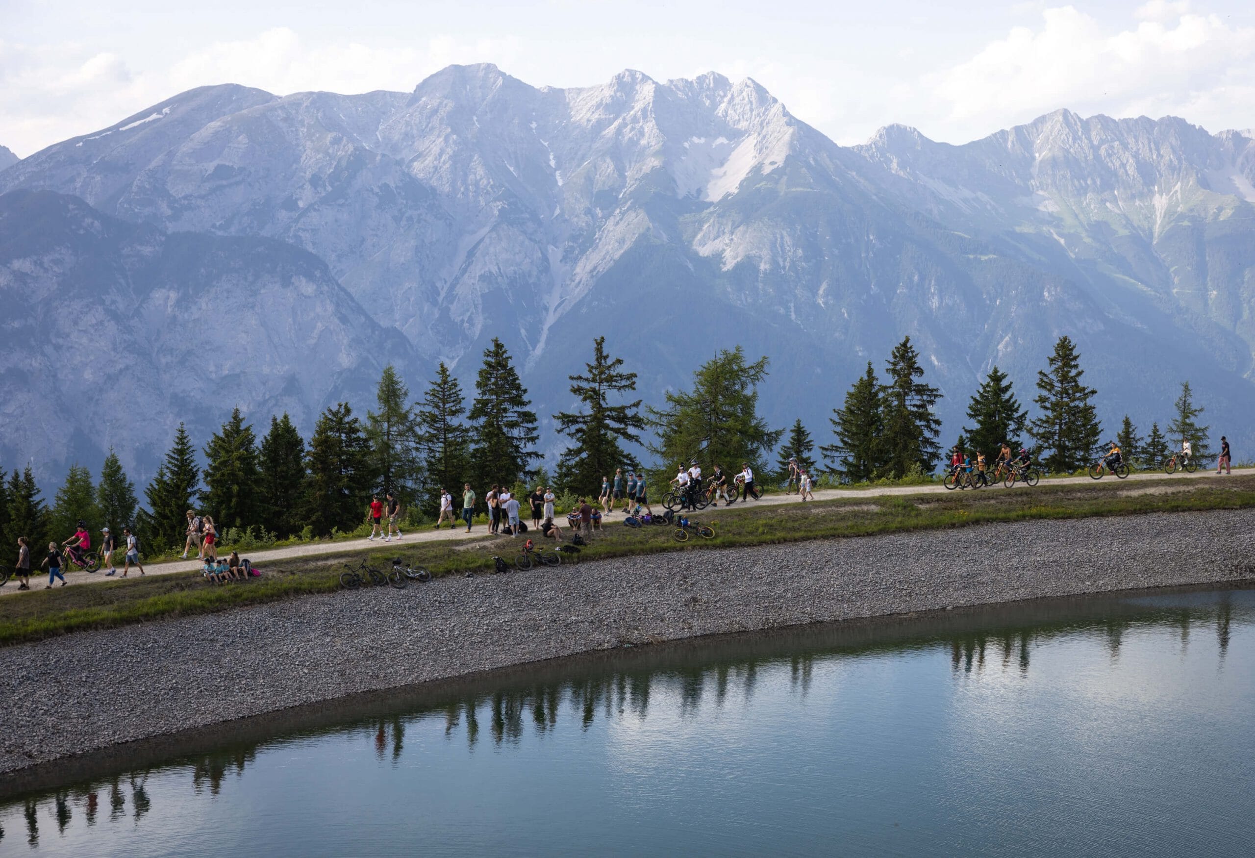 Spectators watch Crankworx beside a lake with Austrian Alps in the background