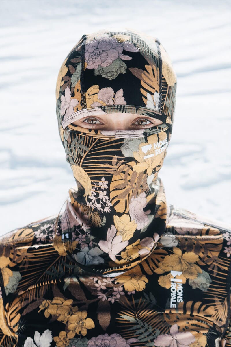 Women stands wearing head to toe Merino thermals and balaclava covered in floral print, you can only see her eyes
